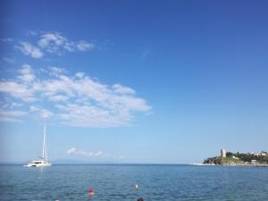 a white boat in the water with a sailboat at Kiwi Kastle in Nea Fokea