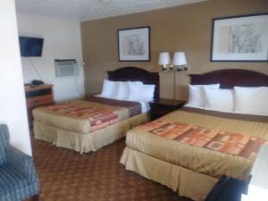 a hotel room with two beds and a couch at Garden Inn & Suites New Braunfels in New Braunfels