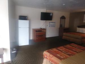 a hotel room with two beds and a refrigerator at Garden Inn & Suites New Braunfels in New Braunfels