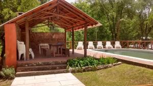 a pavilion with a table and chairs next to a pool at Cabañas Buen Dia in Villa Serranita