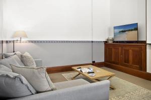 a living room with a couch and a table and a tv at Seal Rocks Lighthouse Cottages in Seal Rocks