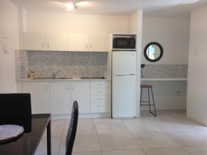 a kitchen with a refrigerator and a microwave at Chez Noosa Resort Motel in Sunshine Beach