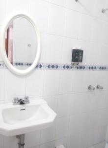 Baño blanco con lavabo y espejo en Hotel Santa Rosa, en Ayacucho