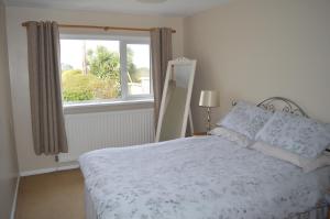 a white bedroom with a bed with a window at Drumahaman Cottage in Ballycastle