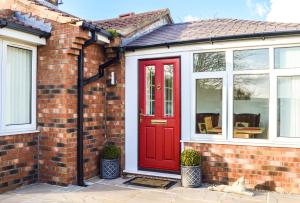 a brick house with a red door and windows at The Darling Suites in Filey