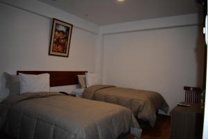 a hotel room with two beds and a picture on the wall at Casa De Luz Hotel in Machu Picchu