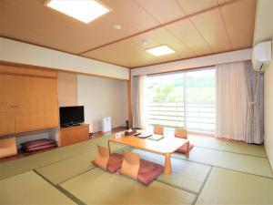 een kamer met een tafel en stoelen en een groot raam bij Mineyama Kogen Hotel Relaxia in Kamikawa