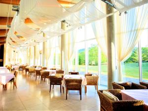 a dining room with tables and chairs and windows at Mineyama Kogen Hotel Relaxia in Kamikawa