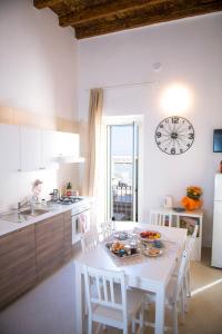 a kitchen with a white table and chairs and a clock at Dimora Porto Canale in Monopoli