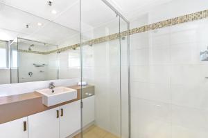 a bathroom with a sink, shower, and mirror at Talisman Apartments in Gold Coast