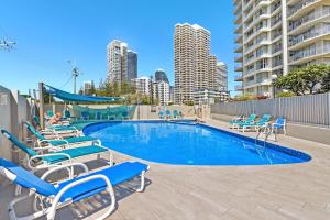 a swimming pool with lounge chairs and a city skyline at Talisman Apartments in Gold Coast