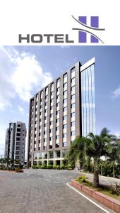 a hotel building with palm trees in front of it at Hotel H - Sandhill Hotels Private Limited in Anand