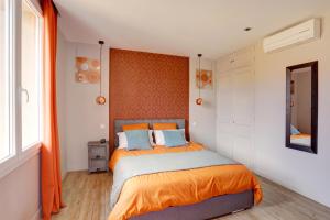 1 dormitorio con 1 cama con sábanas de color naranja y espejo en L'Amandine ,45 m2 terrasse et garage centre ville, en Saint-Raphaël