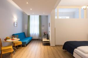プラハにあるDuskova Apartmentsのベッドルーム1室(ベッド1台、テーブル、青いソファ付)