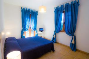 un letto blu in una camera con tende blu di Villette Luisa by SolturElba a Capoliveri