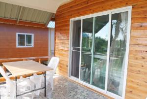 a patio with a table and chairs and a large window at Happy Home Kohjum in Ko Jum