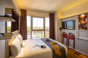 a bedroom with a bed and a large window at ibis Styles - Nairobi, Westlands in Nairobi