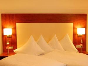 1 cama grande con almohadas blancas y 2 lámparas en las mesas en Hotel Sterkel, en Rödermark