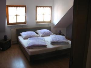 a bedroom with a bed with two pillows and two windows at Ferienwohnung Lautner in Zirndorf