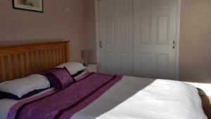 a bedroom with a large bed with purple and white sheets at Myrtle Cottage in Johnshaven