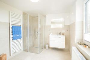 a white bathroom with a shower and a sink at 5 Sterne Ferienhaus Emmelsbüll in Emmelsbüll-Horsbüll +38 photos