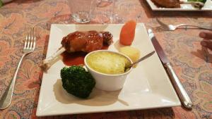 a plate of food with meat and broccoli on a table at Hôtel Restaurant Le Schlossberg in Zellenberg