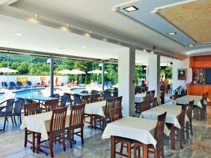 a restaurant with tables and chairs and a swimming pool at Hotel Afroditi in Paralia Panteleimonos