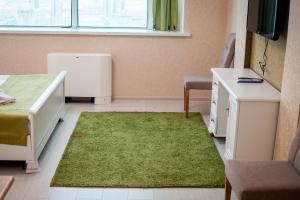 una camera con frigorifero e tappeto verde di Bon Mary Hotel a Astana