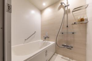 a bathroom with a bath tub and a shower at Nishitetsu Hotel Croom Nagoya in Nagoya