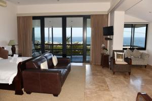 a hotel room with a bed and a couch and chairs at 51 On Camps Bay in Cape Town