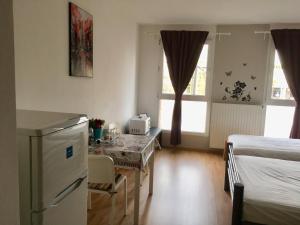 ブダペストにあるBudapest Baross Apartmentのベッド2台、テーブル、冷蔵庫が備わる客室です。