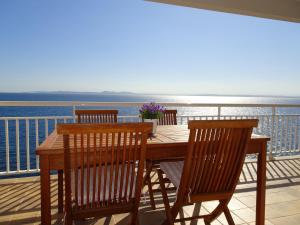 una mesa de madera y sillas en un balcón con vistas al agua en Apartament Belvedere, en Roses