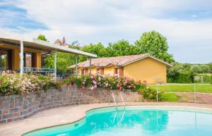 ein Haus mit einem Pool neben einer Backsteinmauer in der Unterkunft Le Macerine in Castiglione del Lago