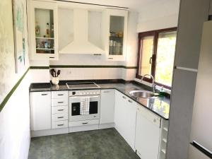 a kitchen with white cabinets and a sink at Somo Surfskate hostel in Castanedo
