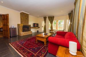 a living room with a red couch and a fireplace at Game Haven Lodge in Blantyre
