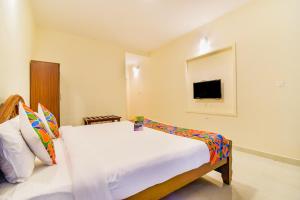 een slaapkamer met een bed en een tv aan de muur bij FabHotel Vinu Valley Resorts in Ooty