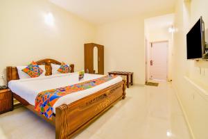 een slaapkamer met een groot bed en een flatscreen-tv bij FabHotel Vinu Valley Resorts in Ooty
