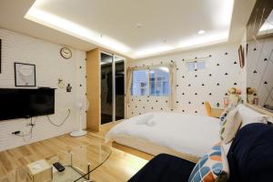 um quarto com uma cama branca e uma televisão em Color Fun inn em Kaohsiung