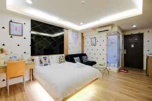 a bedroom with a large white bed and a desk at Color Fun inn in Kaohsiung