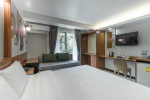 ein Hotelzimmer mit einem Bett und einem Sofa in der Unterkunft Cozytel Chiangmai in Chiang Mai