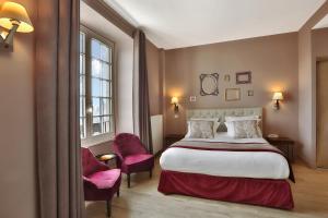 een hotelkamer met een bed en twee roze stoelen bij Hôtel Joyet de Maubec in Uzerche