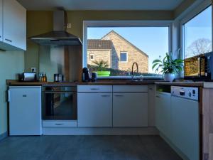 uma cozinha com electrodomésticos brancos e uma grande janela em Luxurious Cottage in Aywaille with Sauna and bubble bath em Aywaille