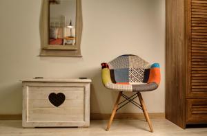 einen Stuhl neben einer Kommode und einem Spiegel in der Unterkunft Melody Apartman in Eger