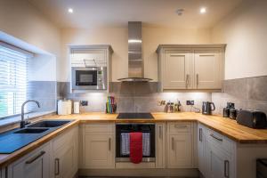 a kitchen with white cabinets and a sink and a microwave at Lochsie Cottage in Portree