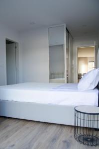 een slaapkamer met een groot wit bed en een tafel bij Antónia's house in Ponte de Lima