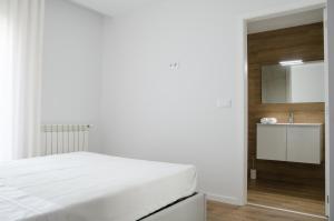 a white bedroom with a bed and a sink at Antónia's house in Ponte de Lima