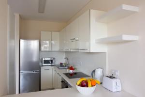 a kitchen with white cabinets and a bowl of fruit at Opera Exclusive Apts by TrulyCyprus in Limassol