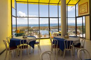 - deux tables et des chaises dans une chambre avec une grande fenêtre dans l'établissement Yacht Lago Titicaca, à Ichu
