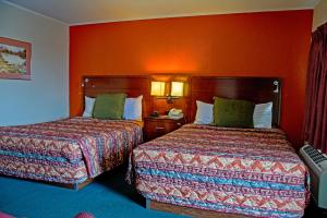 two beds in a hotel room with orange walls at America's Best Inn and Suites Emporia in Emporia