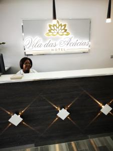 a woman sitting at a desk with a sign that reads villas ashanti hotel at Jardim das Acácias in Maputo